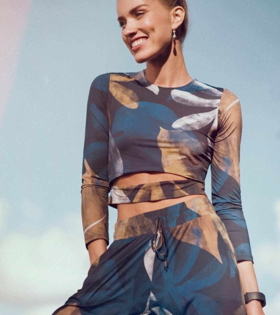 Uma mulher usando uma blusa e calça um brinco e sorrindo